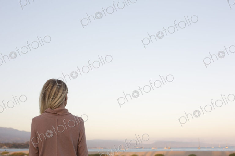 Blond woman standing at the ocean.
