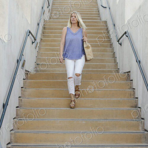 Blond woman walking down a staircase.