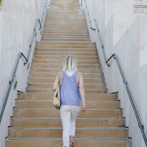 Blond woman walking up a staircase.