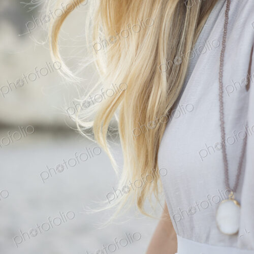 Blond woman wearing a dress and necklace on a sandy beach. Blond woman wearing a dress and necklace on a sandy beach.