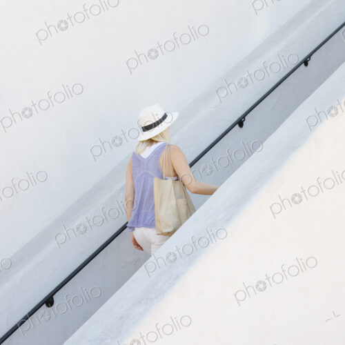 Blond woman wearing a hat walking up a staircase. Blond woman wearing a hat walking up a staircase.