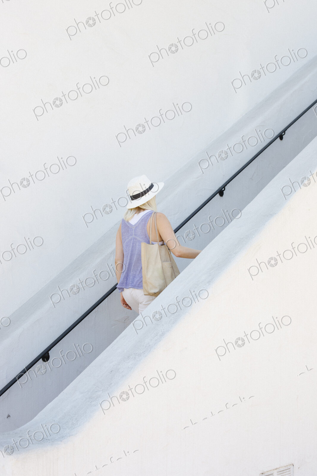 Blond woman wearing a hat walking up a staircase.