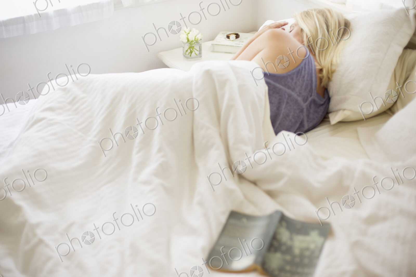 Blonde woman sleeping in a bed with white linen.