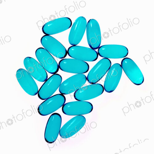 Blue oblong gel pill capsules. Arranged in a pattern.