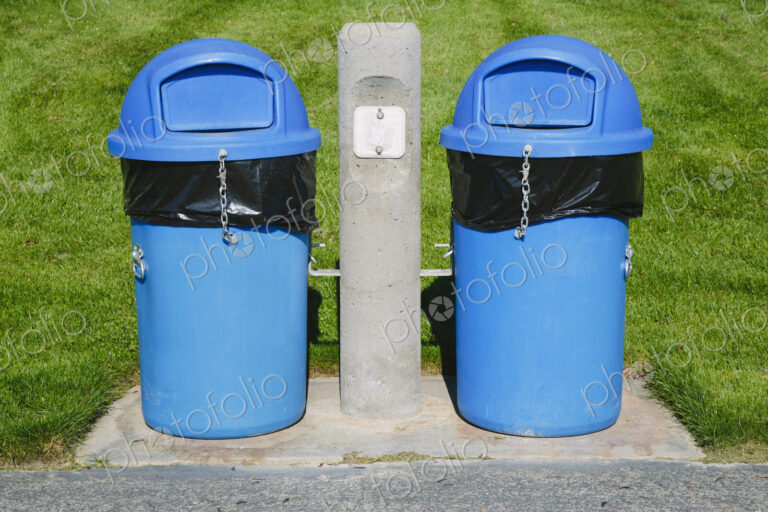 Blue trash cans on a grass sports field.