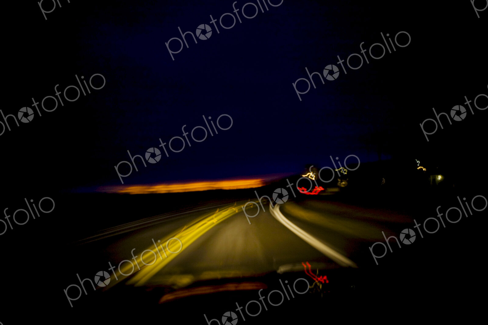 Blurred driver’s view of a roadway at night through the windshield.