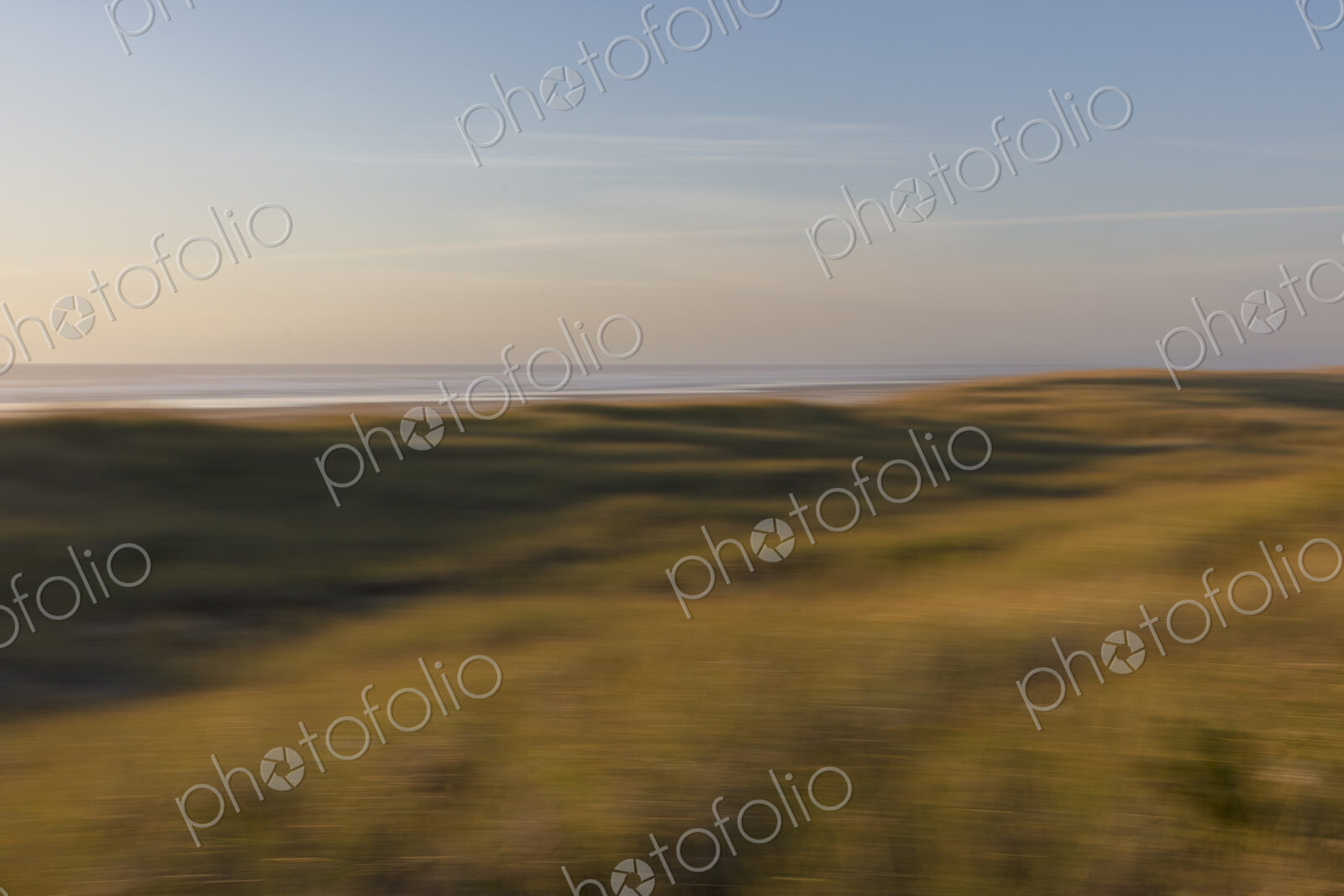 Blurred motion abstract of expansive field of beach grasses, ocean and beach in distance.
