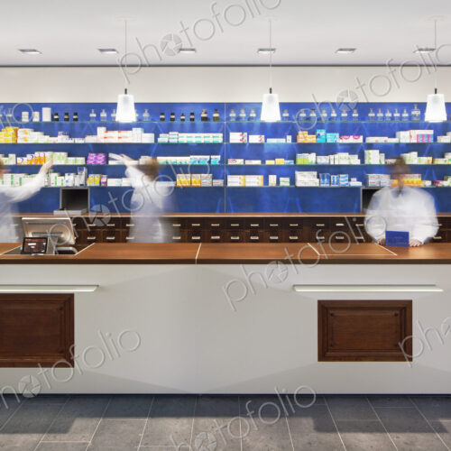 Blurred view of pharmacists behind counter in modern pharmacy