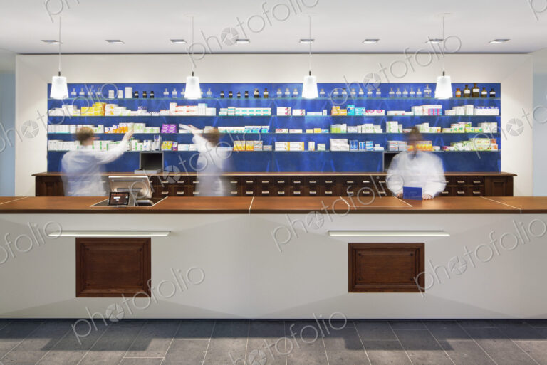 Blurred view of pharmacists behind counter in modern pharmacy