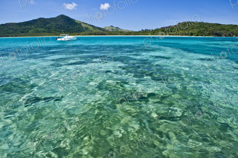 Boat Anchored Offshore Of A Tropical Island