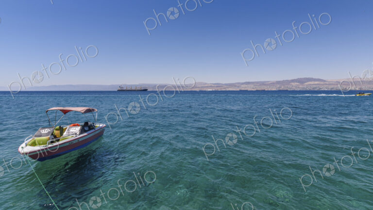 Boat moored in the Red Sea, Jordan, with coastline in the distance.