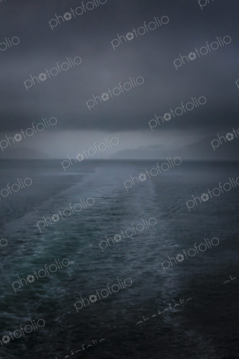 Boat wake behind San Juan Islands ferry on a stormy day with black clouds.