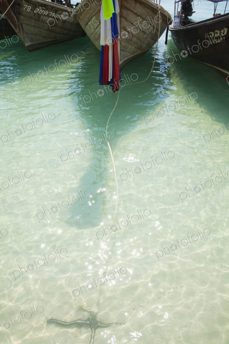 Boats moored with flag and rope in ocean.