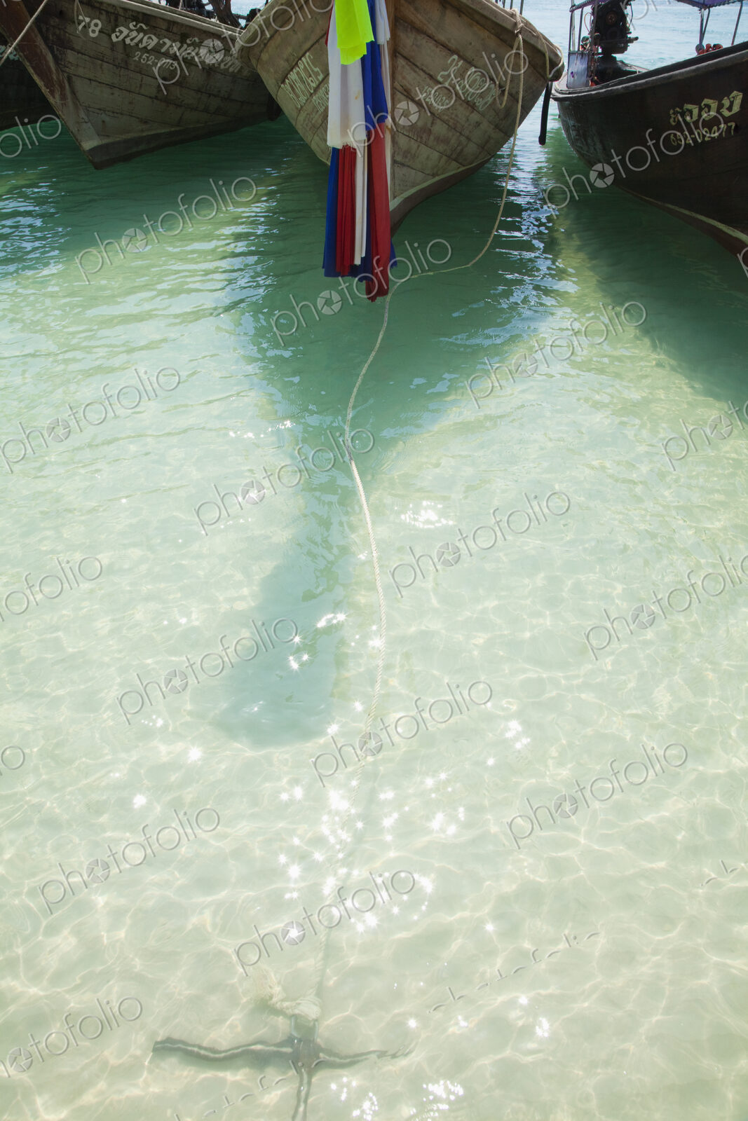 Boats moored with flag and rope in ocean.