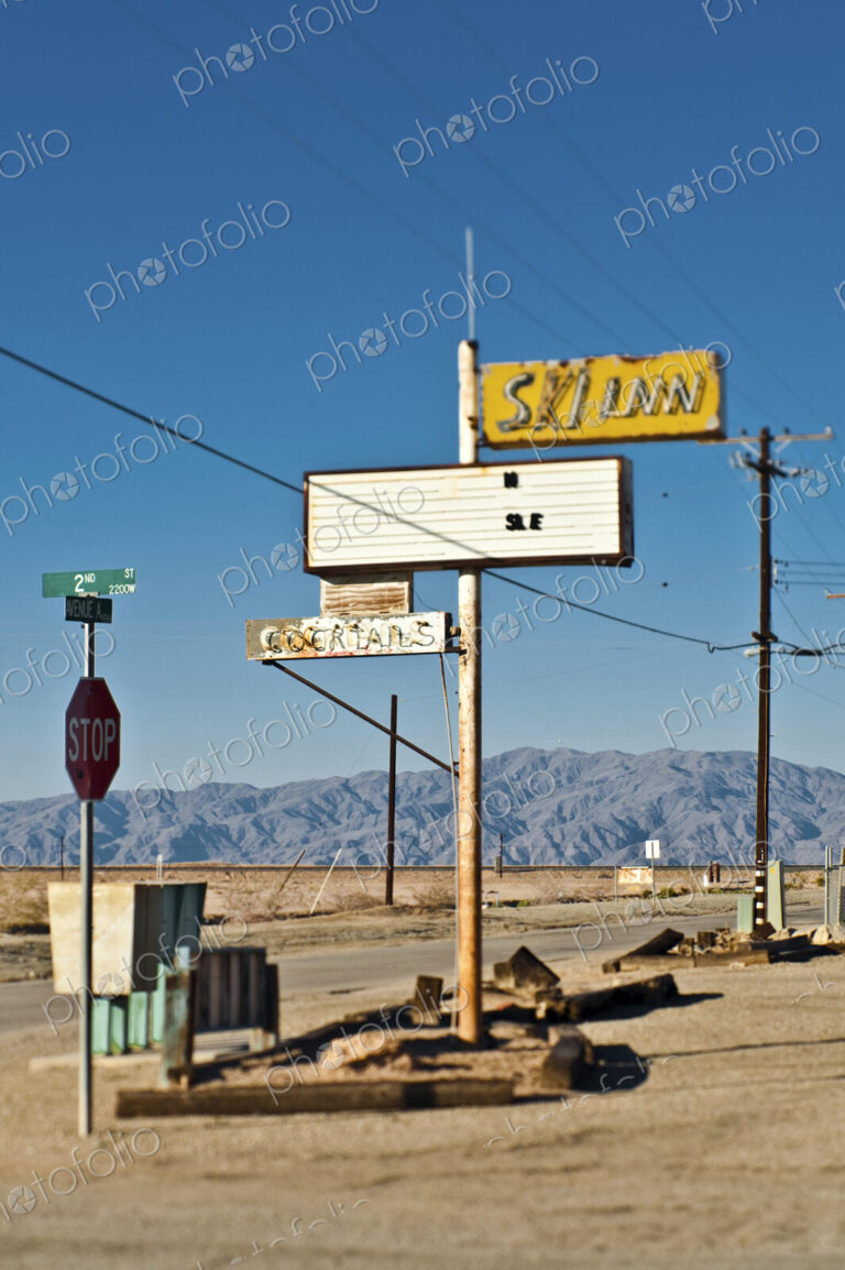 Bombay Beach, California, old neon signs, a stop sign and telephone wires and pole.…