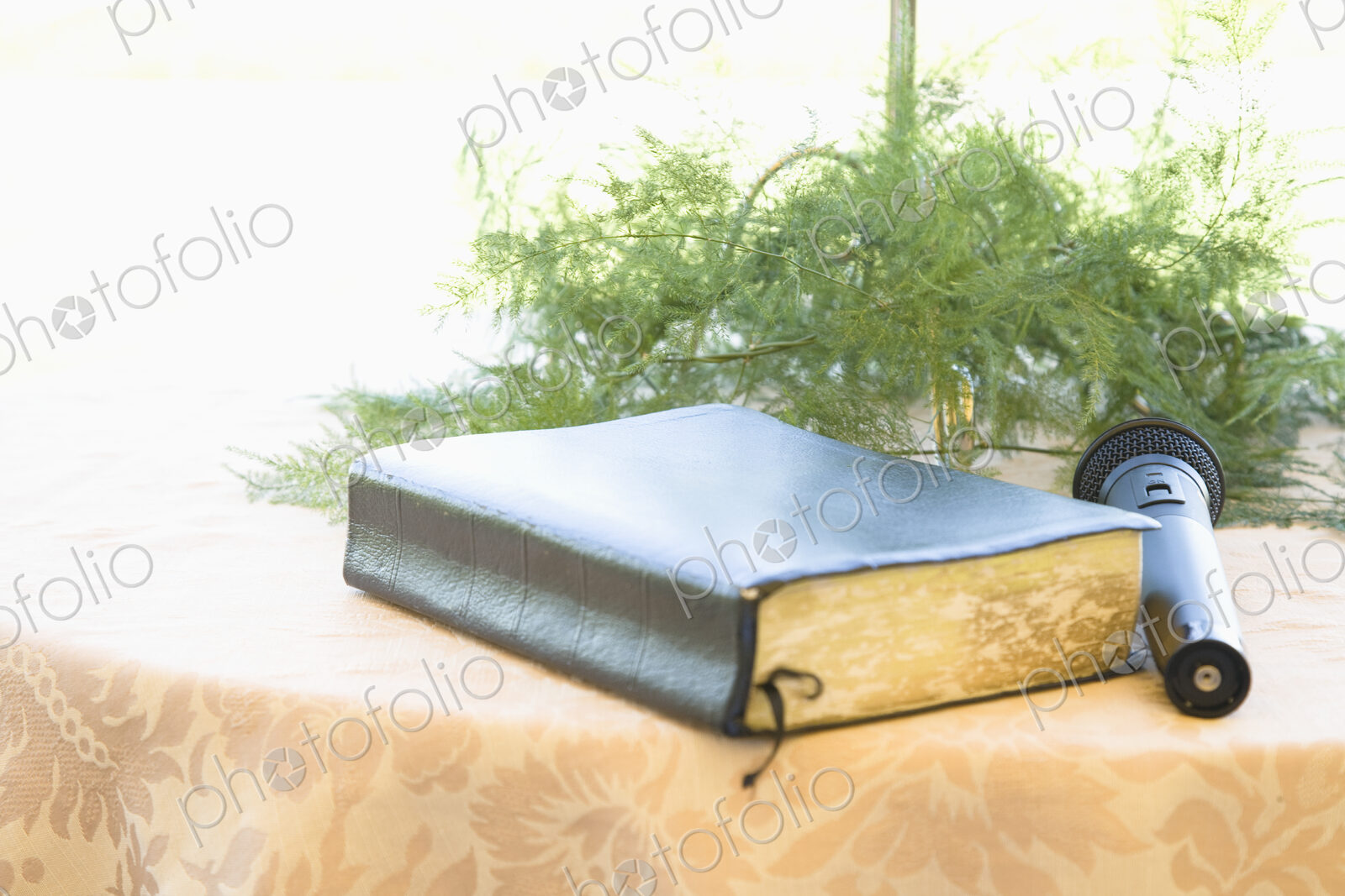 Book and microphone on table with floral arrangement.
