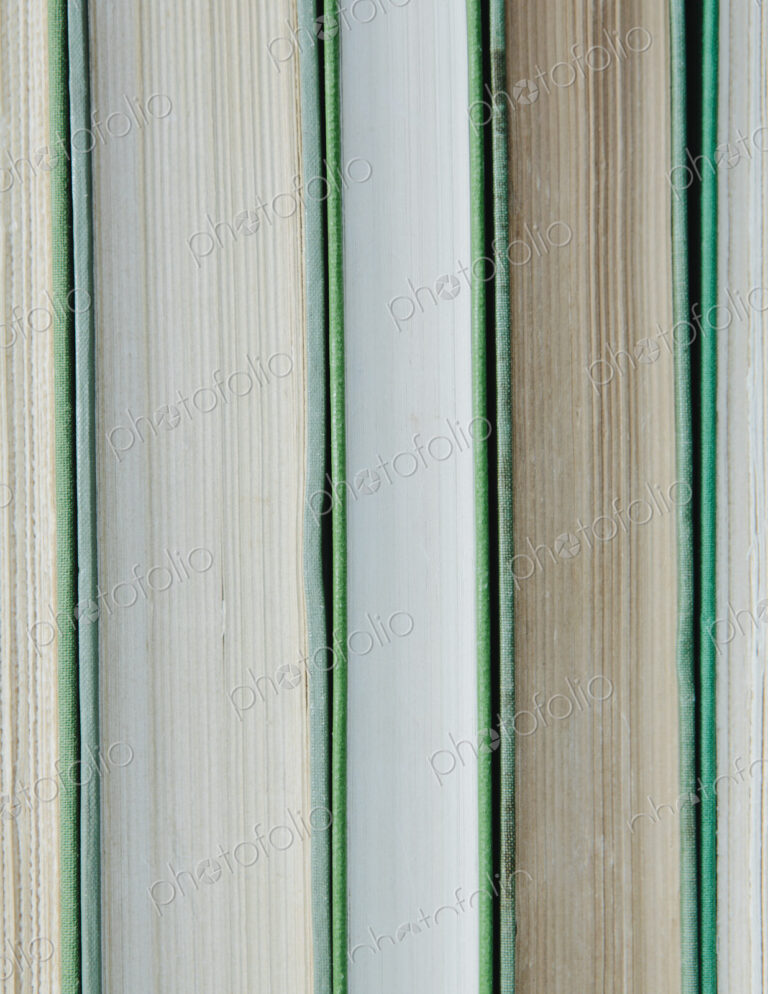 Books in a row, with green hard covers, and white and beige paper edges.