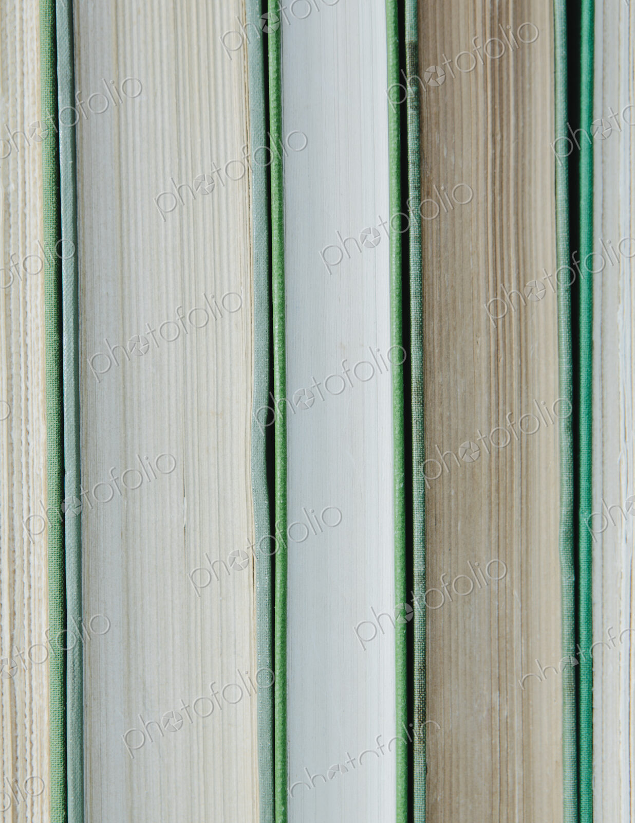 Books in a row, with green hard covers, and white and beige paper edges.