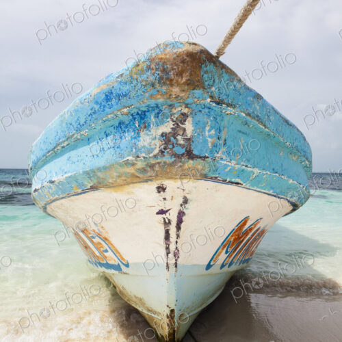 Bow of fishing boat with wooden painted hull on beach.