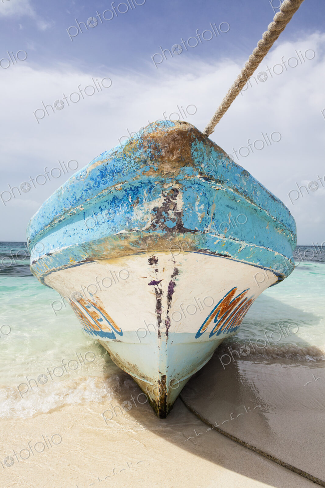 Bow of fishing boat with wooden painted hull on beach.