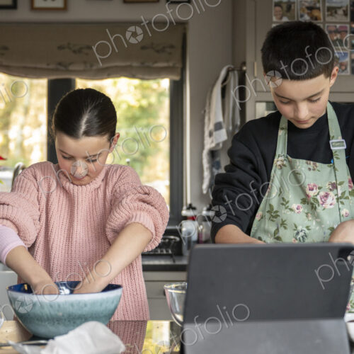Boy and girl baking together in kitchen using tablet. Boy and girl baking together in kitchen using tablet.