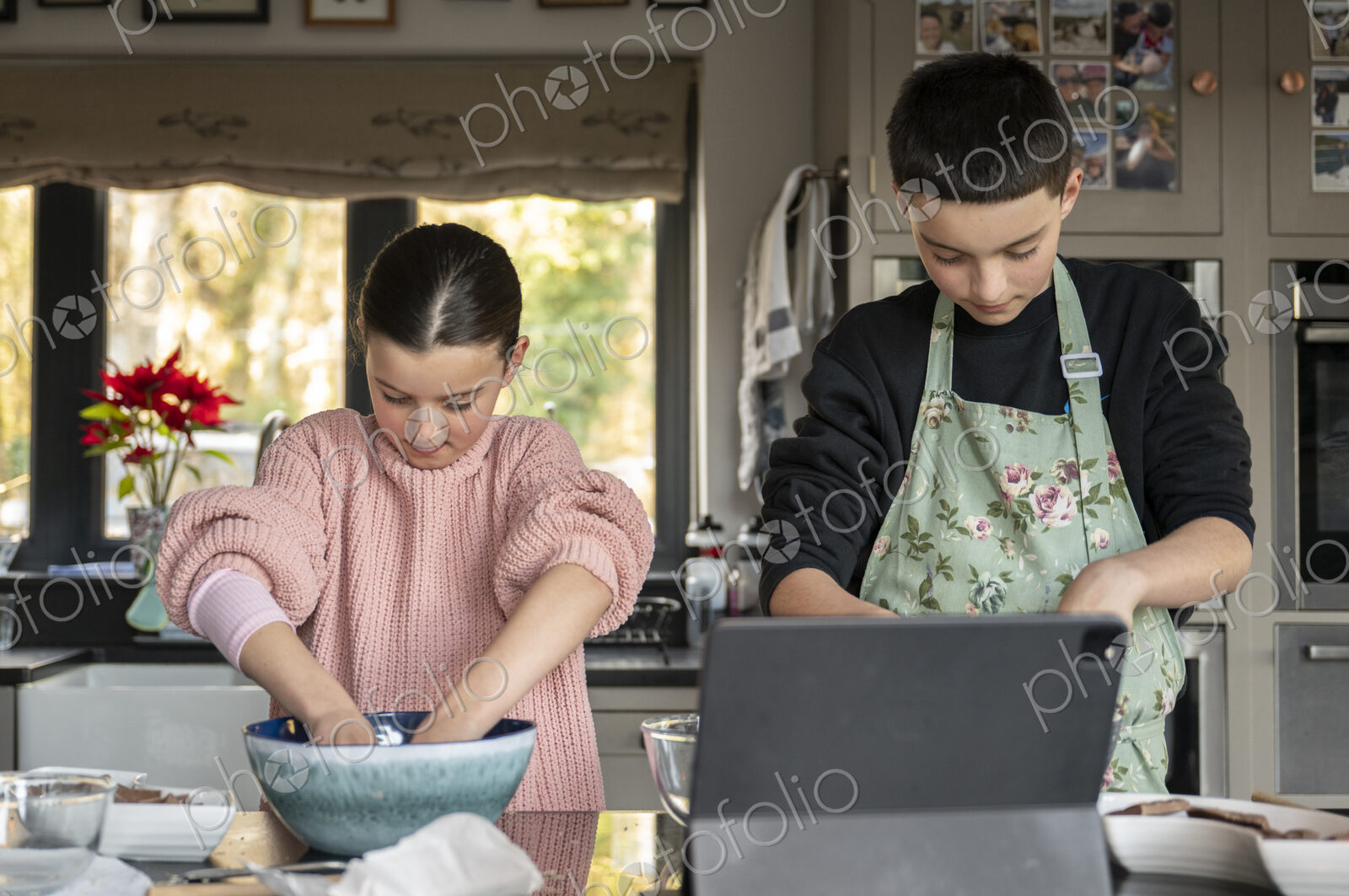 Boy and girl baking together in kitchen using tablet.