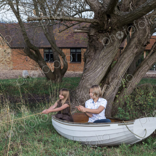 Boy and girl playing in fishing boat on land, fishing in pond by house. Boy and girl playing in fishing boat on land, fishing in pond by house.