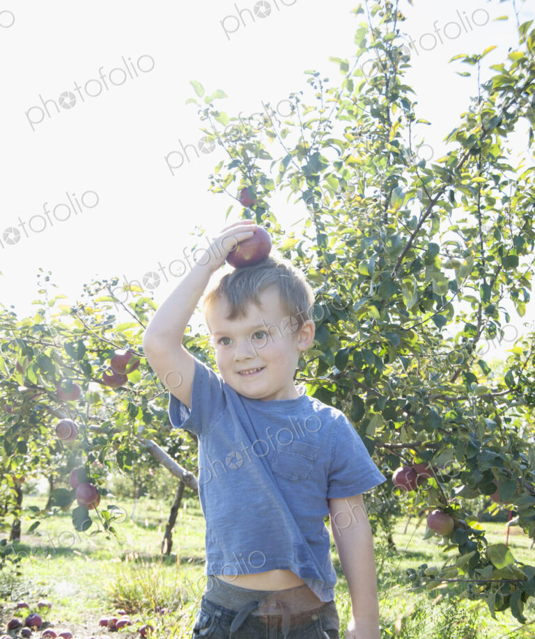 Boy balancing apple on head in orchard