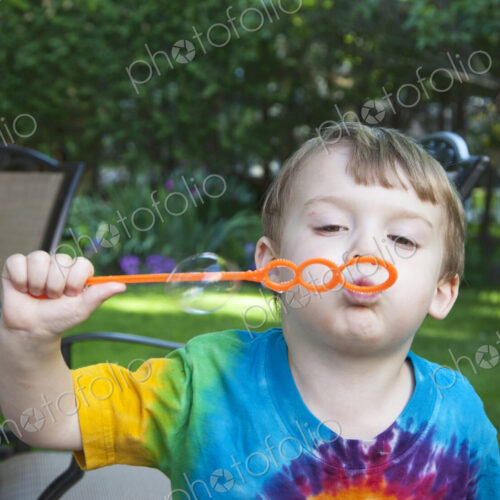 Boy blowing bubbles in backyard Boy blowing bubbles in backyard
