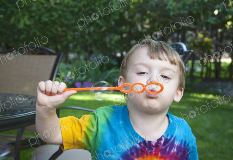 Boy blowing bubbles in backyard