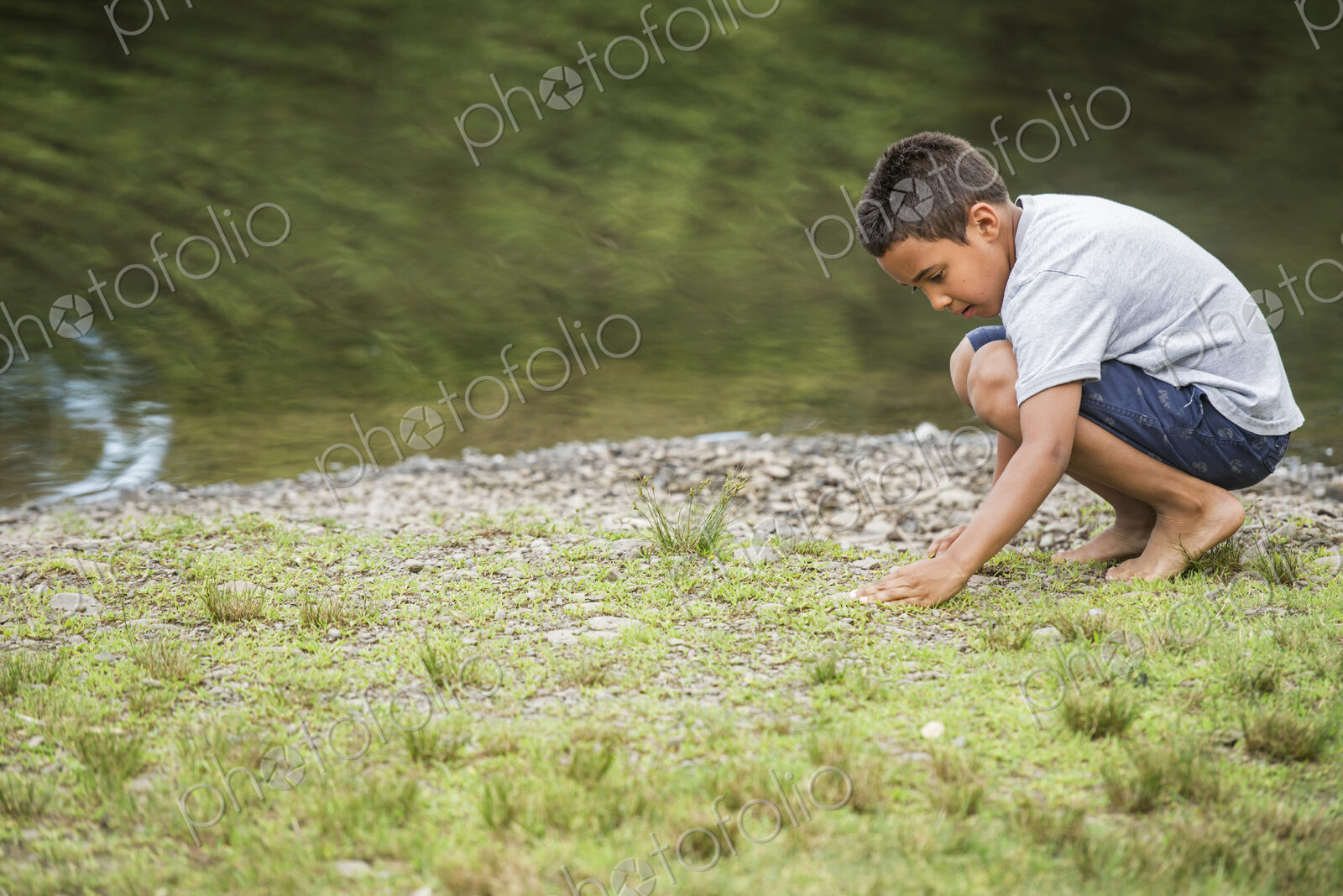 Boy playing by a lake.