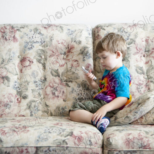 Boy playing with cell phone on sofa Boy playing with cell phone on sofa