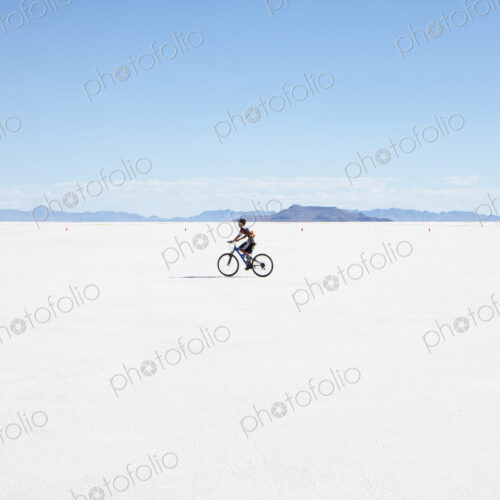 Boy riding bike on salt flats, during Speed Week Boy riding bike on salt flats, during Speed Week