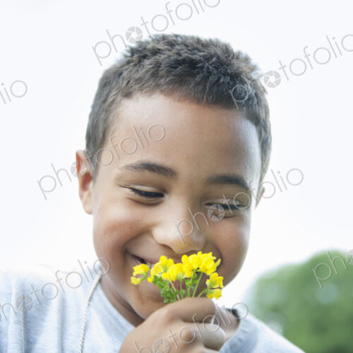Boy smiling and holding flower.