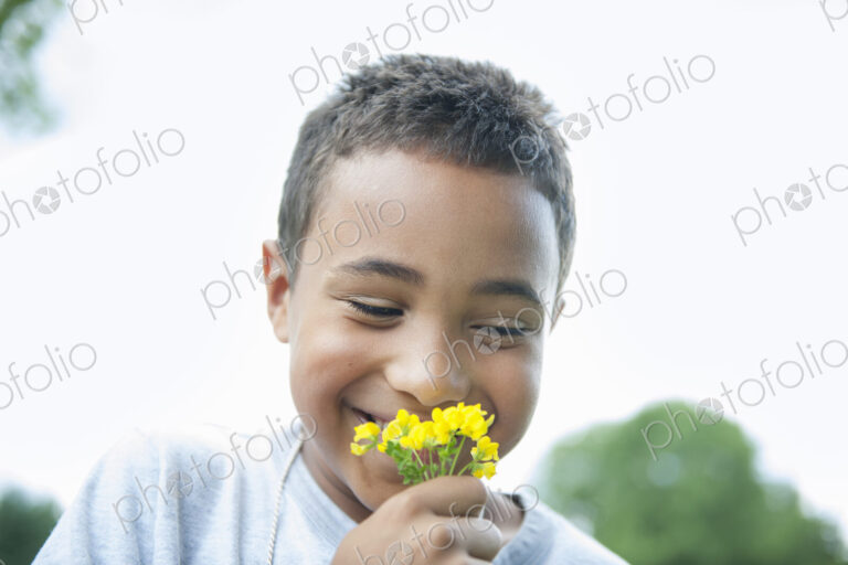 Boy smiling and holding flower.