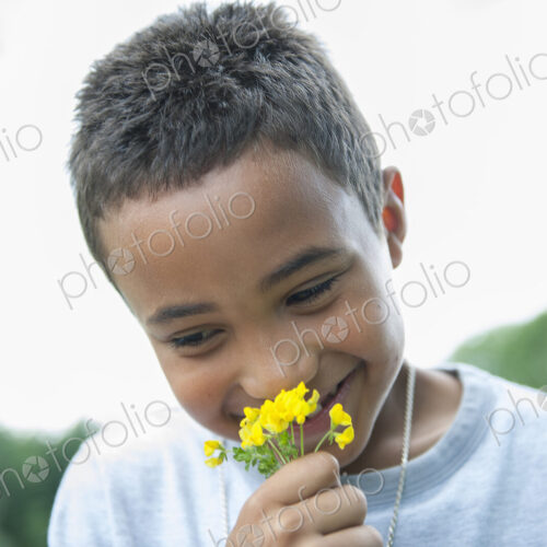 Boy smiling and holding flower.