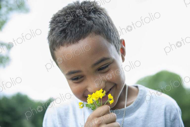 Boy smiling and holding flower.