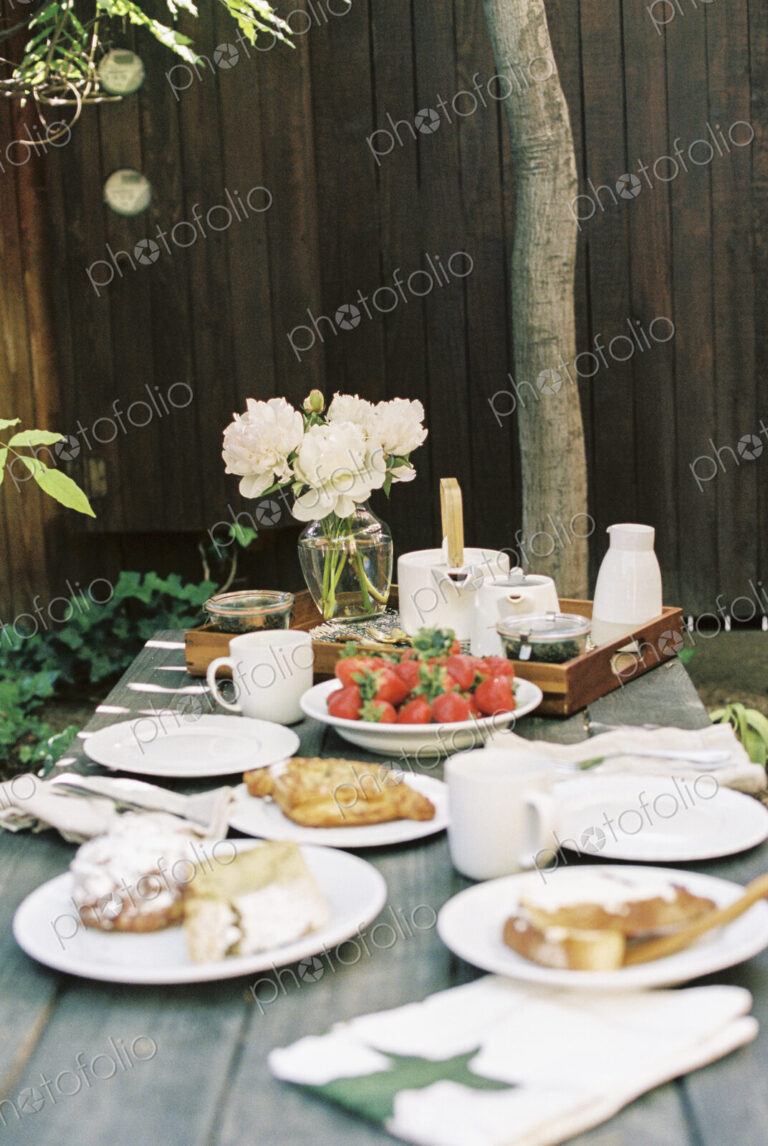 Breakfast table with tea, pastries and fresh strawberries.