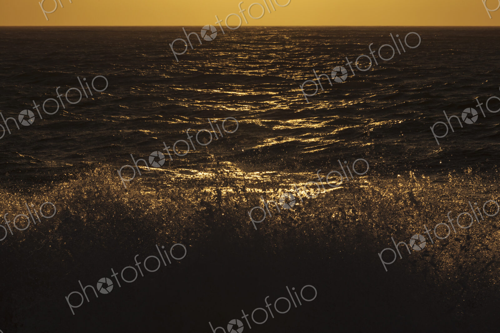 Breaking ocean waves and reflections of light on the water aqt dusk.