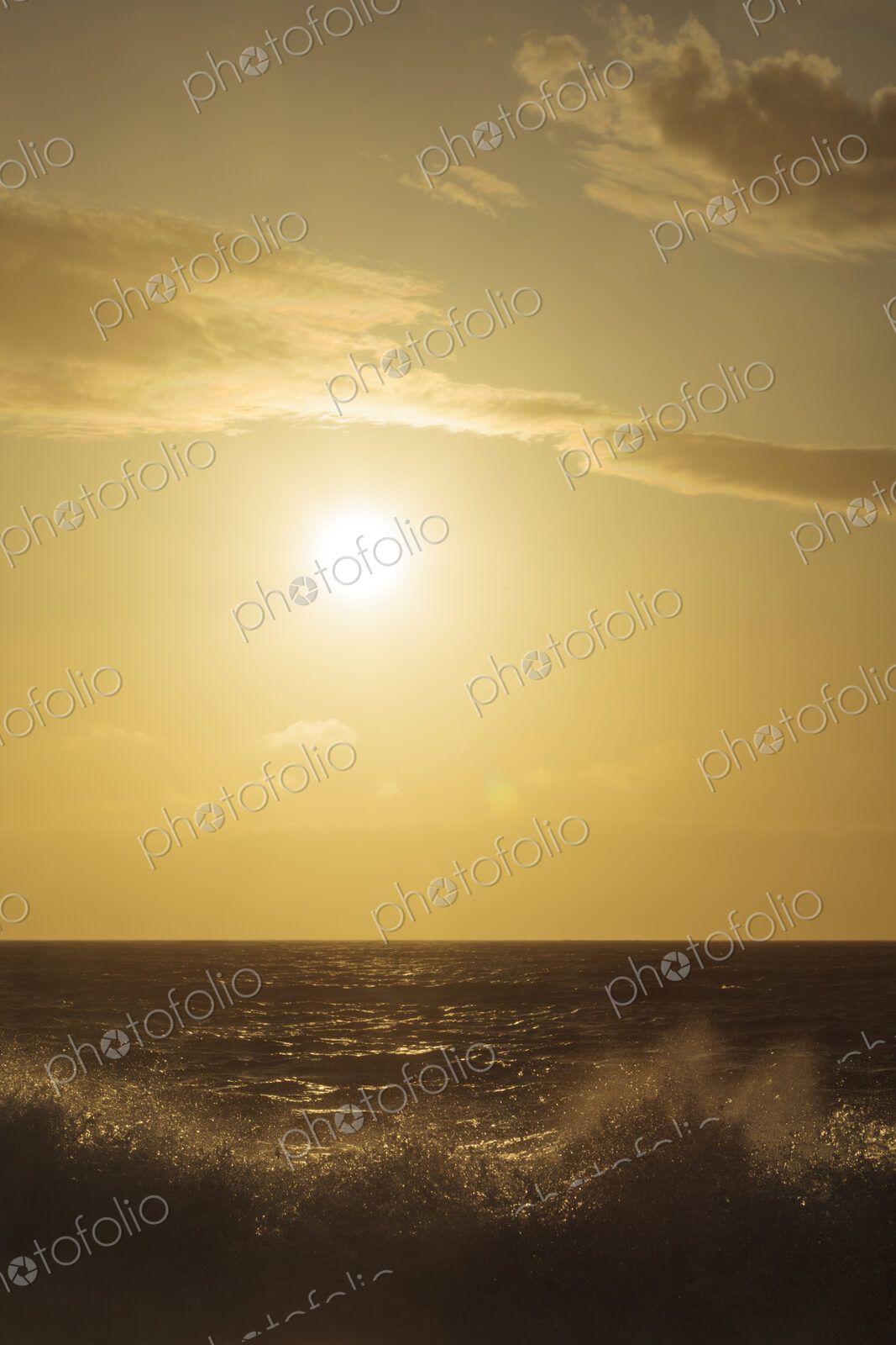 Breaking ocean waves, reflections and white water, a bright sun in the sky