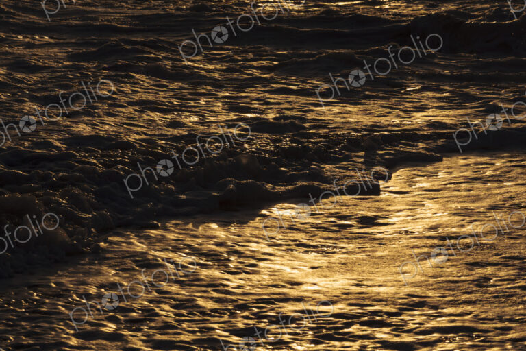 Breaking ocean waves, shadows and light reflections on the water surface.