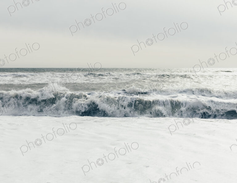 Breaking waves, surf in the ocean and waves, moody overcast sky above