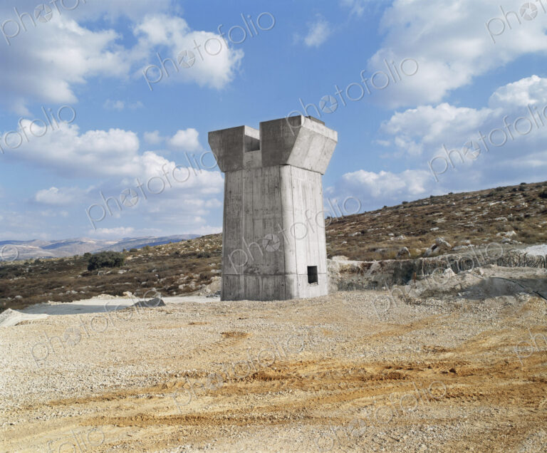 Bridge under construction, pillars and elevated road across an arid landscape.
