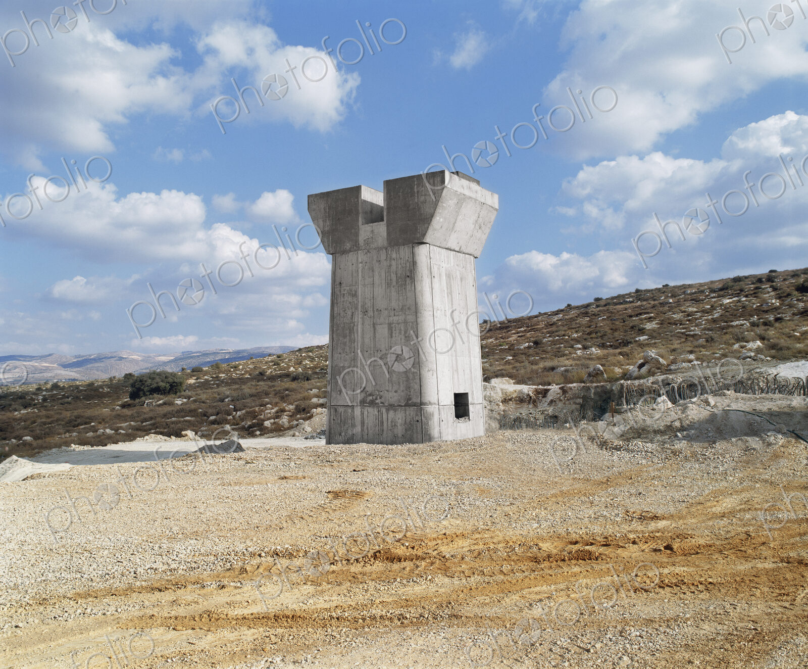 Bridge under construction, pillars and elevated road across an arid landscape.