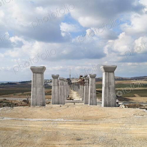 Bridge under construction, pillars and elevated road across an arid landscape. Bridge under construction, pillars and elevated road across an arid landscape.