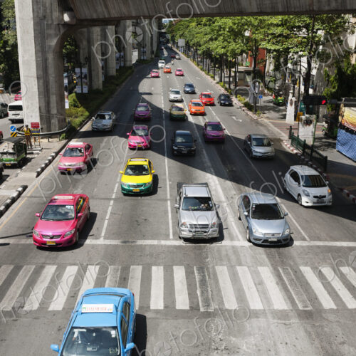 Bright coloured taxis and other cars in Bangkok traffic.