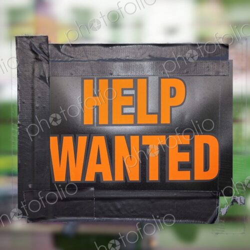 Bright orange "Help Wanted" sign taped to a window, symbolizing job opportunities,… Bright orange "Help Wanted" sign taped to a window, symbolizing job opportunities,…