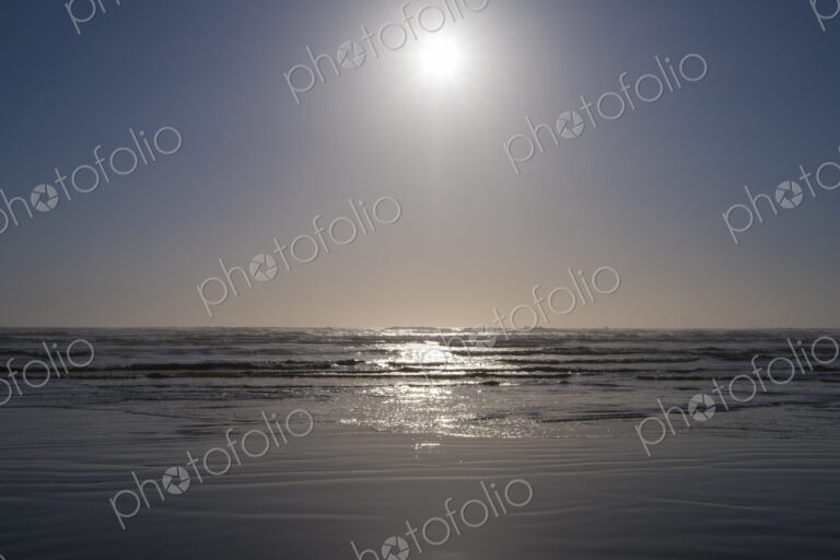 Bright sun over vast ocean and beach