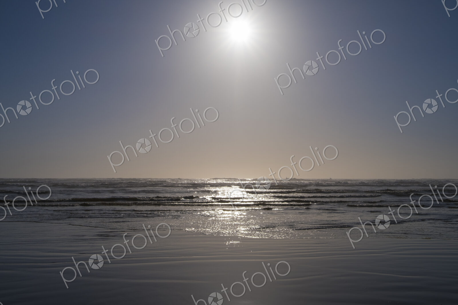 Bright sun over vast ocean and beach