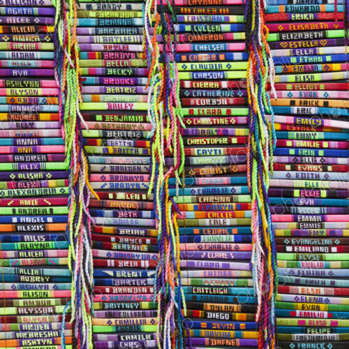 Brightly colored bracelets with embroidered names on a market stall. Brightly colored bracelets with embroidered names on a market stall.